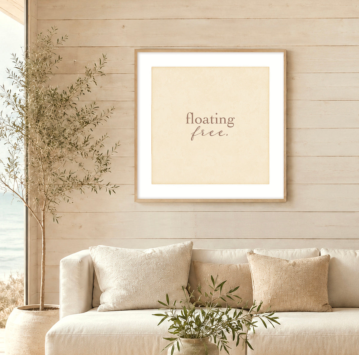 A beige typographical art print that says "floating free" hanging on the wall of a beachy looking house