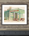 Framed artwork of a beachside building with 'Crystal Cove' sign on a wooden wall.