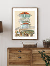 Framed artwork of the Huntington Beach pier above a wooden dresser with decorative items.