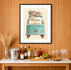 Vintage VW bus with surfboards stacked on the roof rack, coastal surf art print displayed in a bright beach house interior