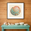 Colorful sea shell resting on sand against a neutral background, minimal coastal art print displayed in a soft beach house interior