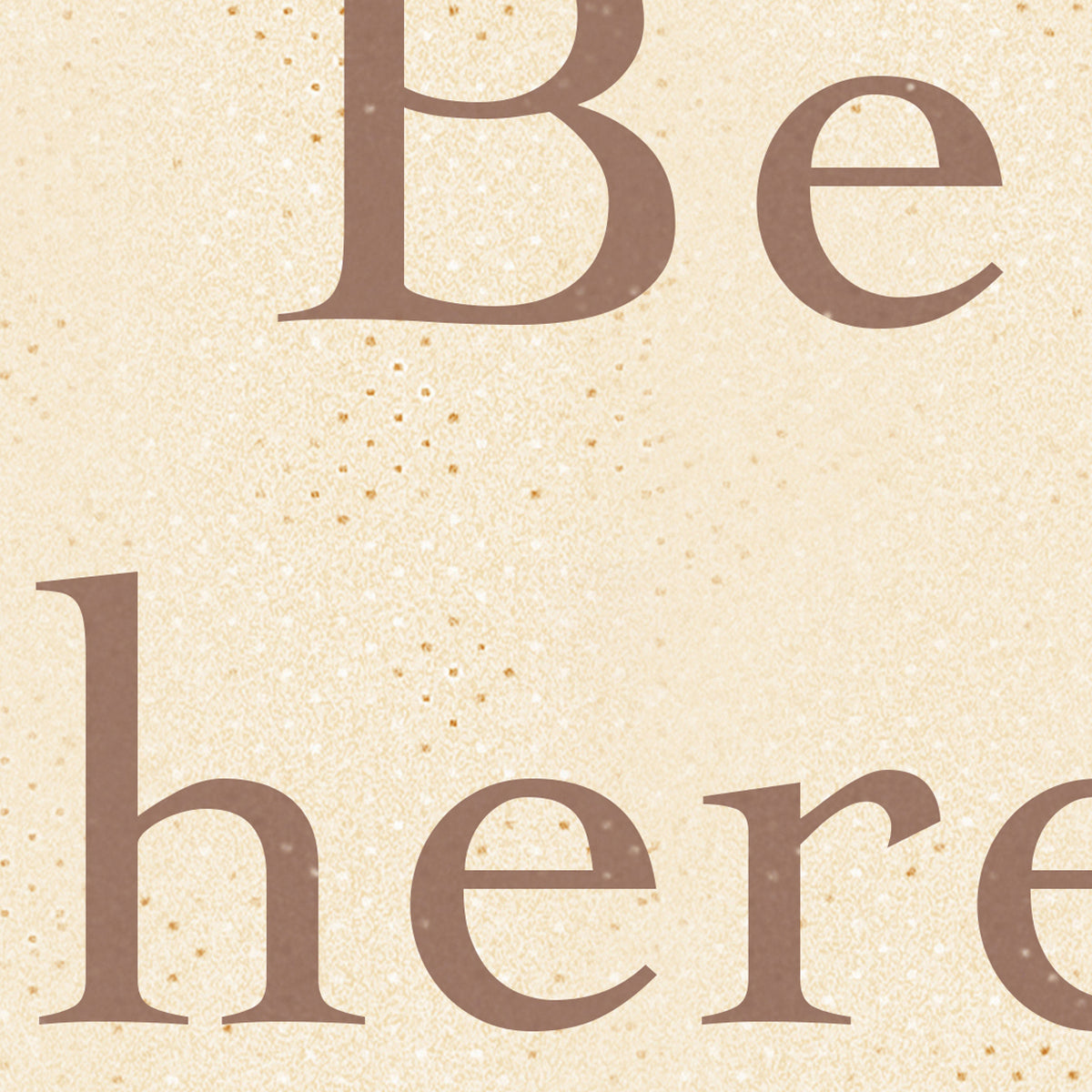 A close-up decorative text design reading 'Be here' in brown serif lettering on a warm beige glitter-textured background.